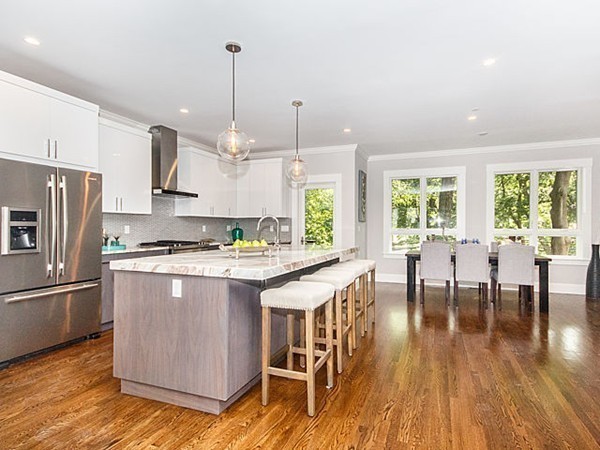 24-26 Beaconsfield Road, Unit 26 Brookline, MA 02445 - Photo 5 of 25 a kitchen with kitchen island granite countertop a stove a refrigerator a dining table and chairs with wooden floor