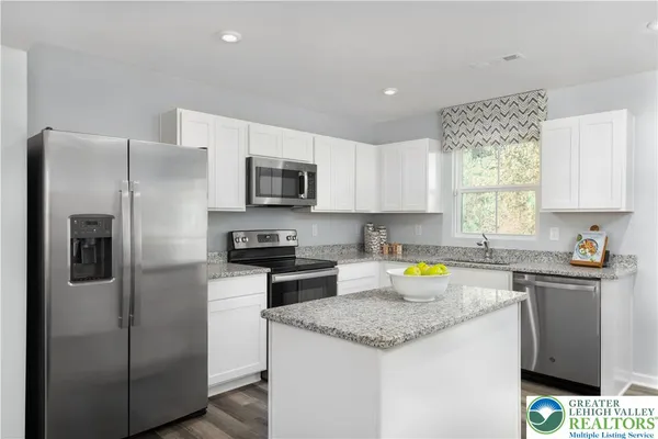 a kitchen with stainless steel appliances granite countertop a refrigerator a stove a sink a microwave and cabinets