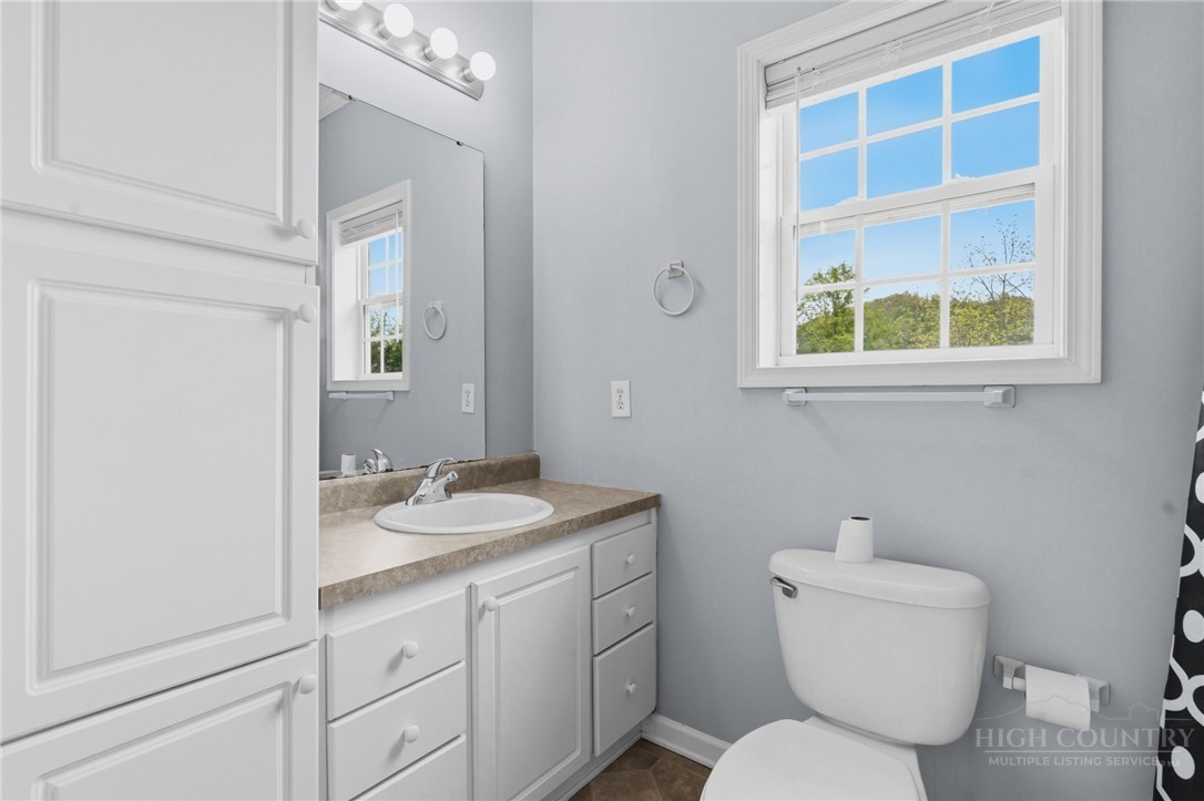 211 Cecil Miller Road, Unit 9 Boone, NC 28607 - Photo 11 of 32 a bathroom with a granite countertop toilet a sink and a mirror