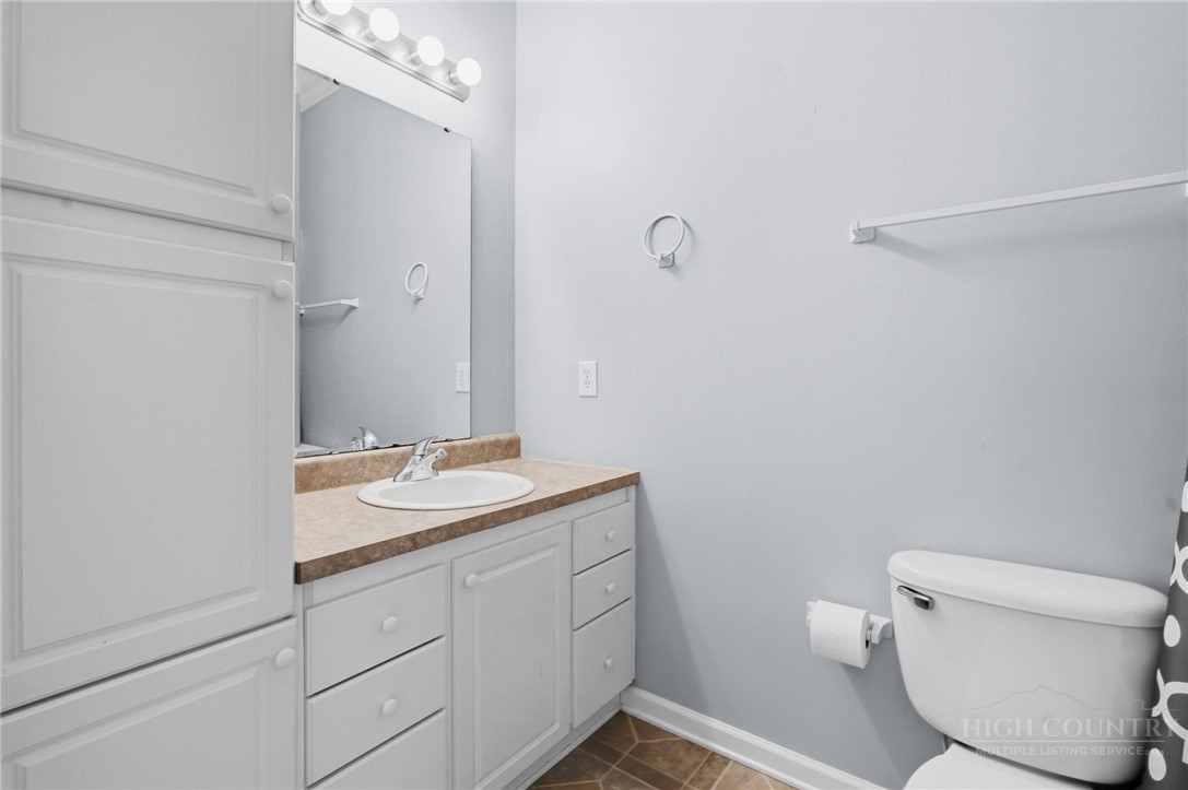 211 Cecil Miller Road, Unit 9 Boone, NC 28607 - Photo 15 of 32 a bathroom with a granite countertop sink a toilet and a mirror