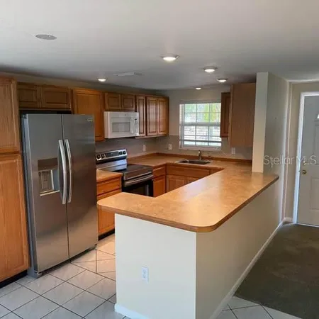 a kitchen with stainless steel appliances granite countertop a sink a stove a refrigerator a washer dryer and white cabinets