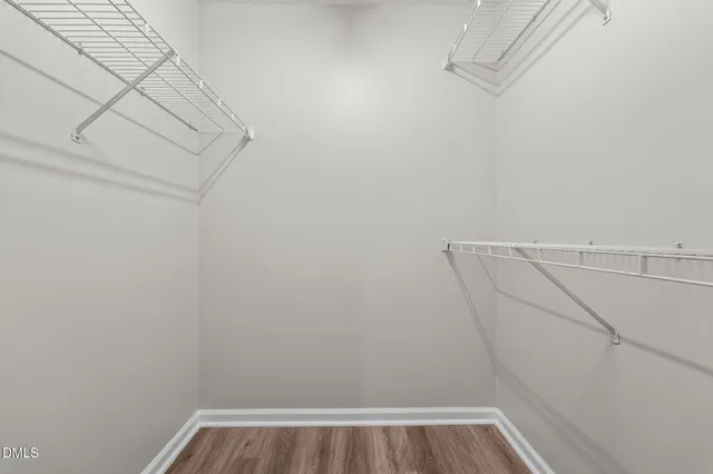 an empty room with wooden floor chandelier fan and closet area