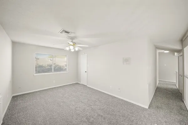 an empty room with a ceiling fan and a window