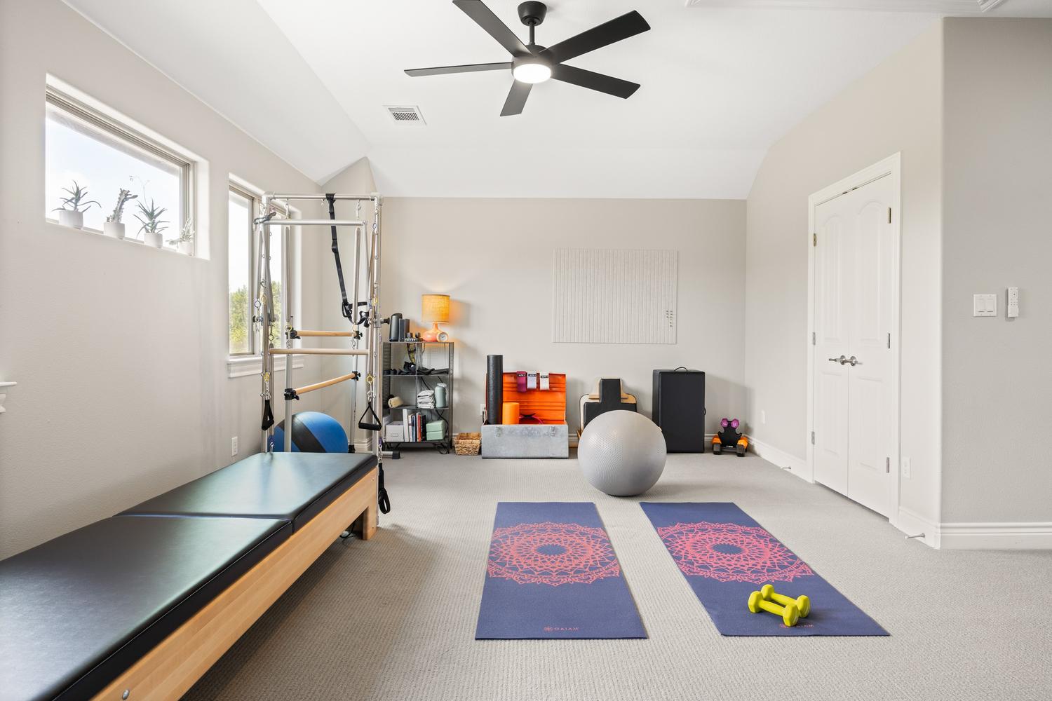 1135 Blue Ridge Drive Dripping Springs, TX 78620 - Photo 25 of 36 An airy exercise room features plush carpeting and a modern ceiling fan, perfect for a home gym.