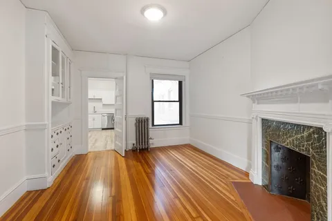 a view of empty room with wooden floor and fireplace