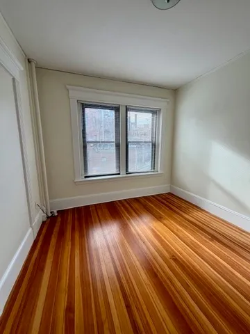 a view of an empty room with wooden floor and window