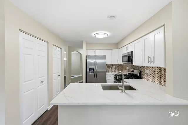 a kitchen with stainless steel appliances a sink a stove a refrigerator cabinets and a dining table