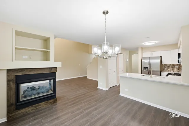a view of a room with wooden floor fire place and kitchen view