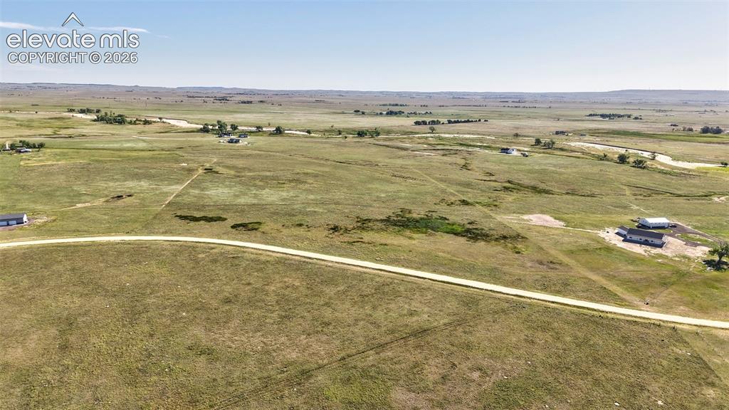 8007 Wrangler Ranch View Peyton, CO 80831 - Photo 9 of 9 Expansive rural landscape featuring a winding dirt road and distant structures