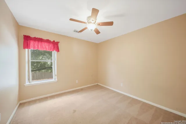 an empty room with windows and ceiling fan