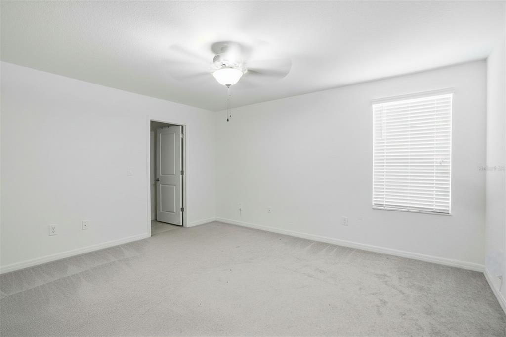 13712 Newbridge Street Spring Hill, FL 34609 - Photo 16 of 35 an empty room with a chandelier fan and windows