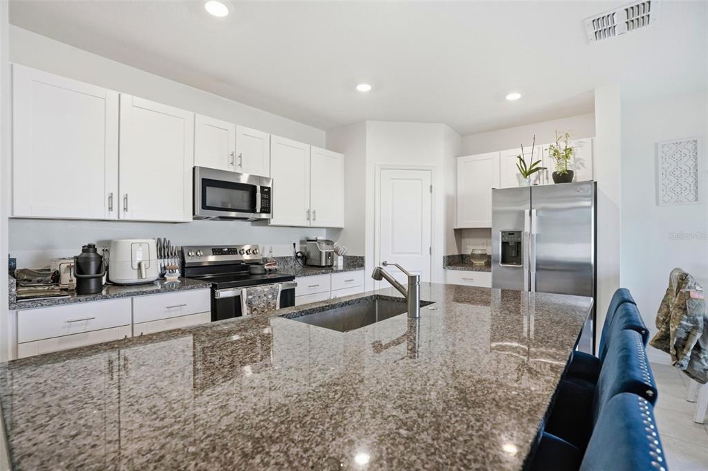 13712 Newbridge Street Spring Hill, FL 34609 - Photo 5 of 35 a kitchen with granite countertop a sink a counter top space appliances and cabinets