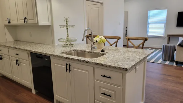 a kitchen with granite countertop a sink a stove and cabinets