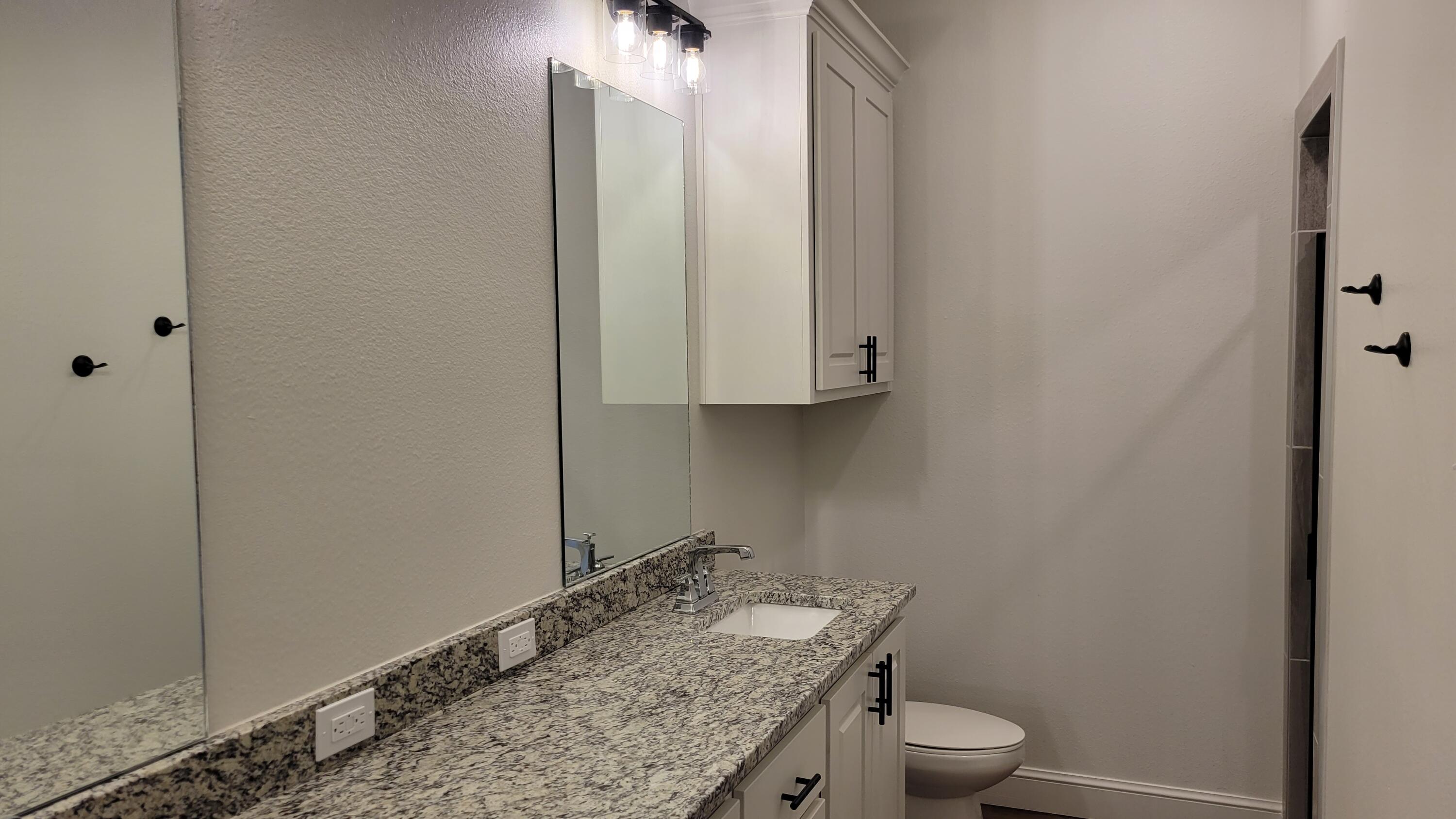 7120 22nd Street Lubbock, TX 79407 - Photo 24 of 40 a bathroom with a granite countertop sink and a toilet