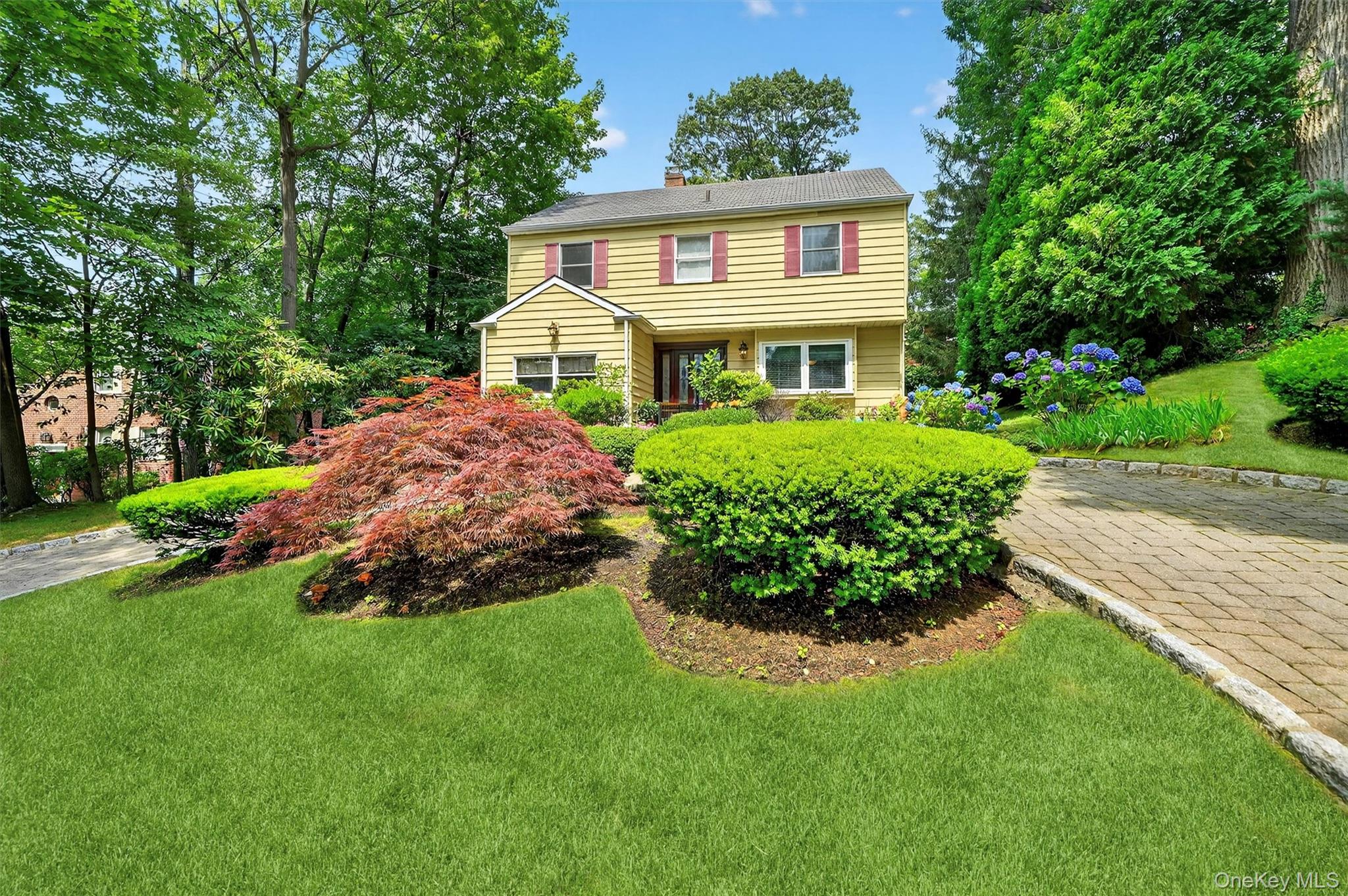Colonial inspired home featuring a front lawn and a chimney