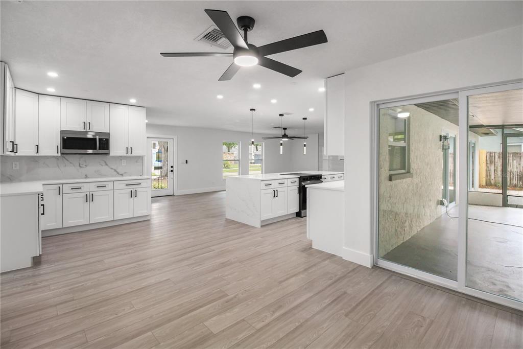 11492 93rd Street Largo, FL 33773 - Photo 16 of 37 a open kitchen with stainless steel appliances granite countertop a refrigerator a stove a sink and white cabinets with wooden floor next to windows