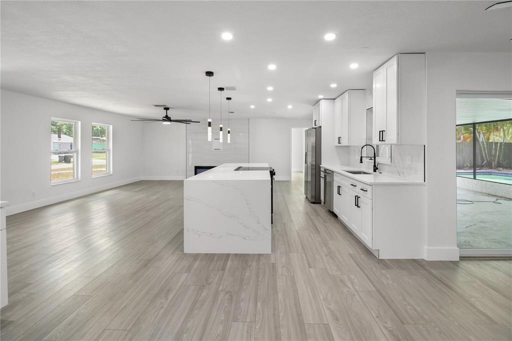 11492 93rd Street Largo, FL 33773 - Photo 18 of 37 a large white kitchen with wooden floors and stainless steel appliances