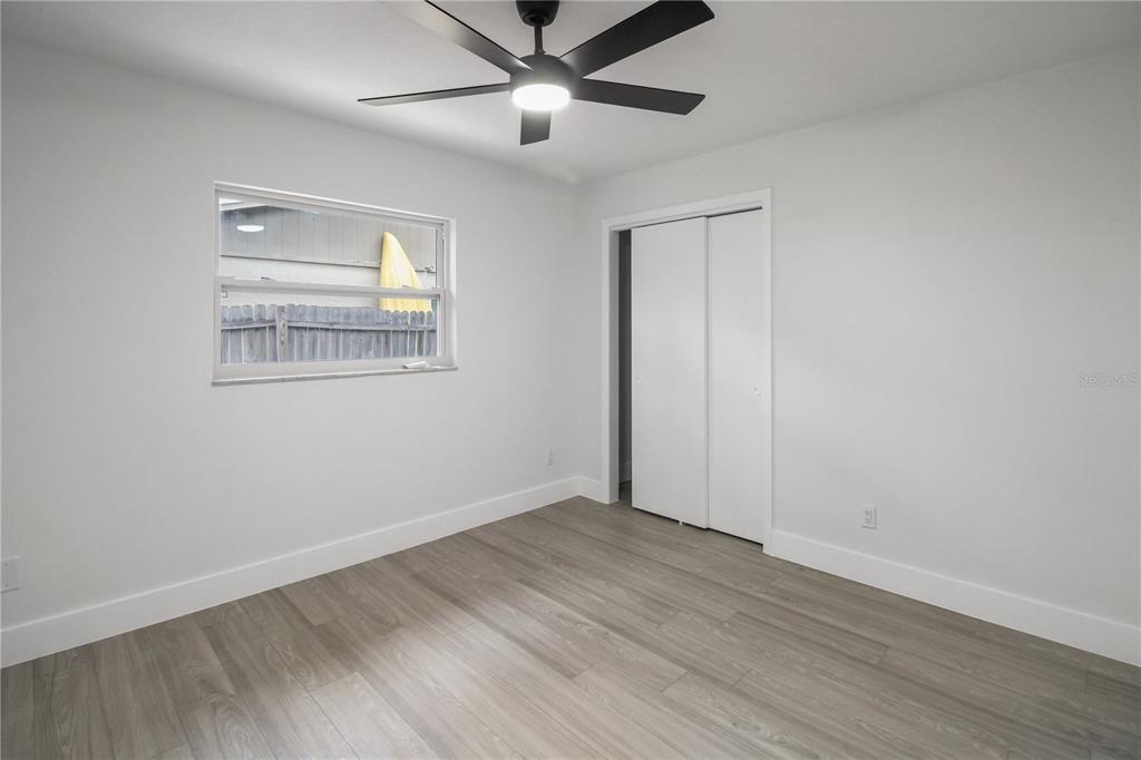 11492 93rd Street Largo, FL 33773 - Photo 19 of 37 a view of an empty room with wooden floor and a ceiling fan