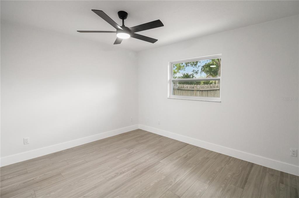 11492 93rd Street Largo, FL 33773 - Photo 24 of 37 an empty room with wooden floor and ceiling fan