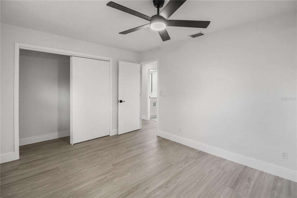 11492 93rd Street Largo, FL 33773 - Photo 25 of 37 an empty room with wooden floor a ceiling fan and closet