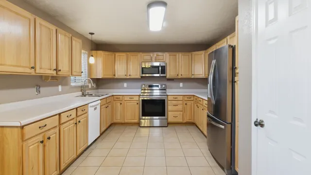 a close view of a refrigerator in kitchen with stainless steel appliances wooden cabinet and large window