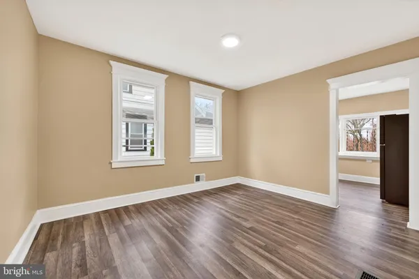 a view of an empty room with window and wooden floor
