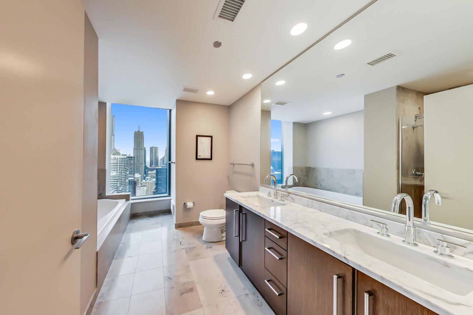60 East Monroe Street, Unit 4404 Chicago, IL 60603 - Photo 11 of 34 a spacious bathroom with a granite countertop sink a toilet a mirror and shower