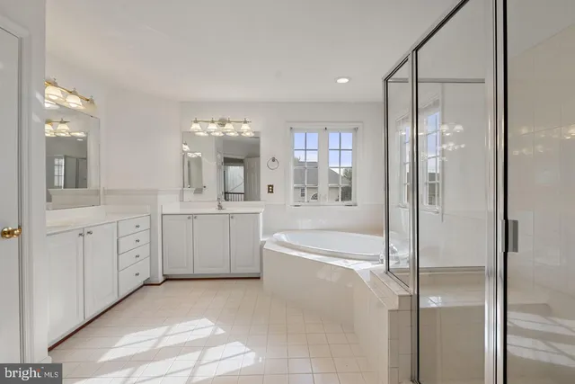 a spacious bathroom with a double vanity sink a mirror a bathtub and shower