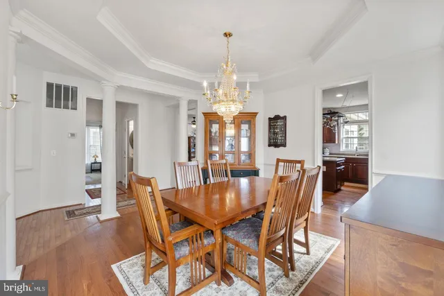 a dining room with wooden floor a chandelier a wooden table and chairs