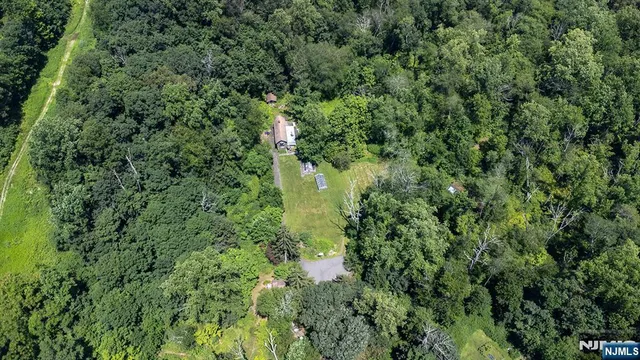 an aerial view of residential house with outdoor space and trees all around