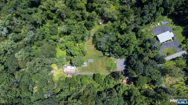 an aerial view of residential house with outdoor space and trees all around