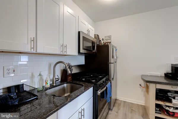 a kitchen with granite countertop a sink stove and refrigerator