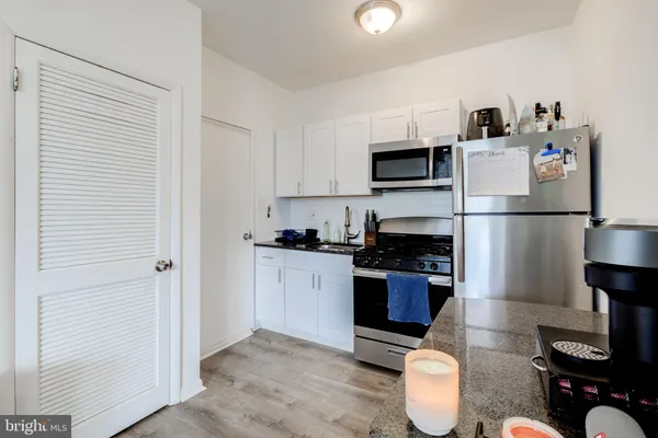 a kitchen with granite countertop a refrigerator stove and microwave