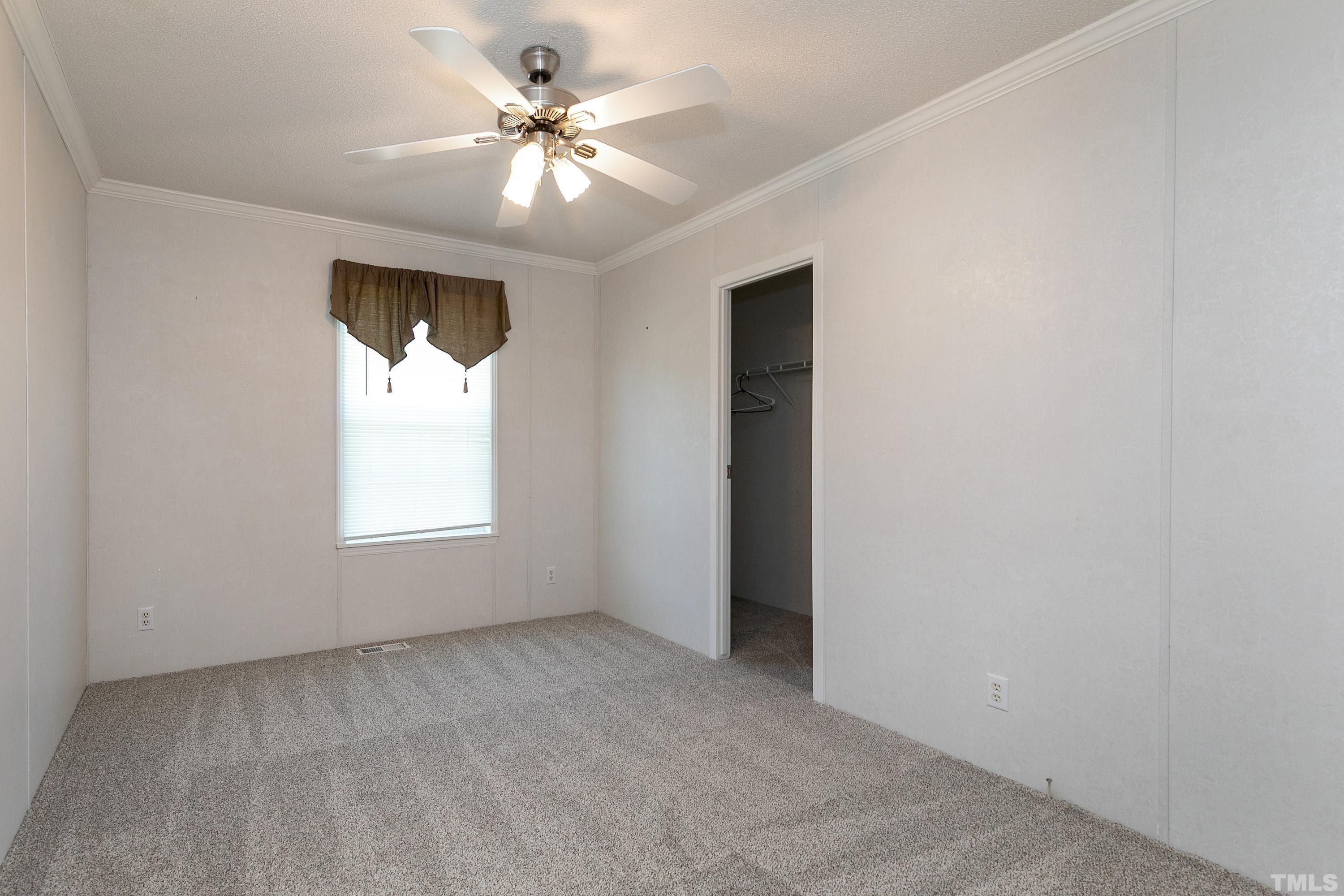 8308 South Creek Road Willow Spring, NC 27592 - Photo 26 of 42 an empty room with a chandelier fan and windows