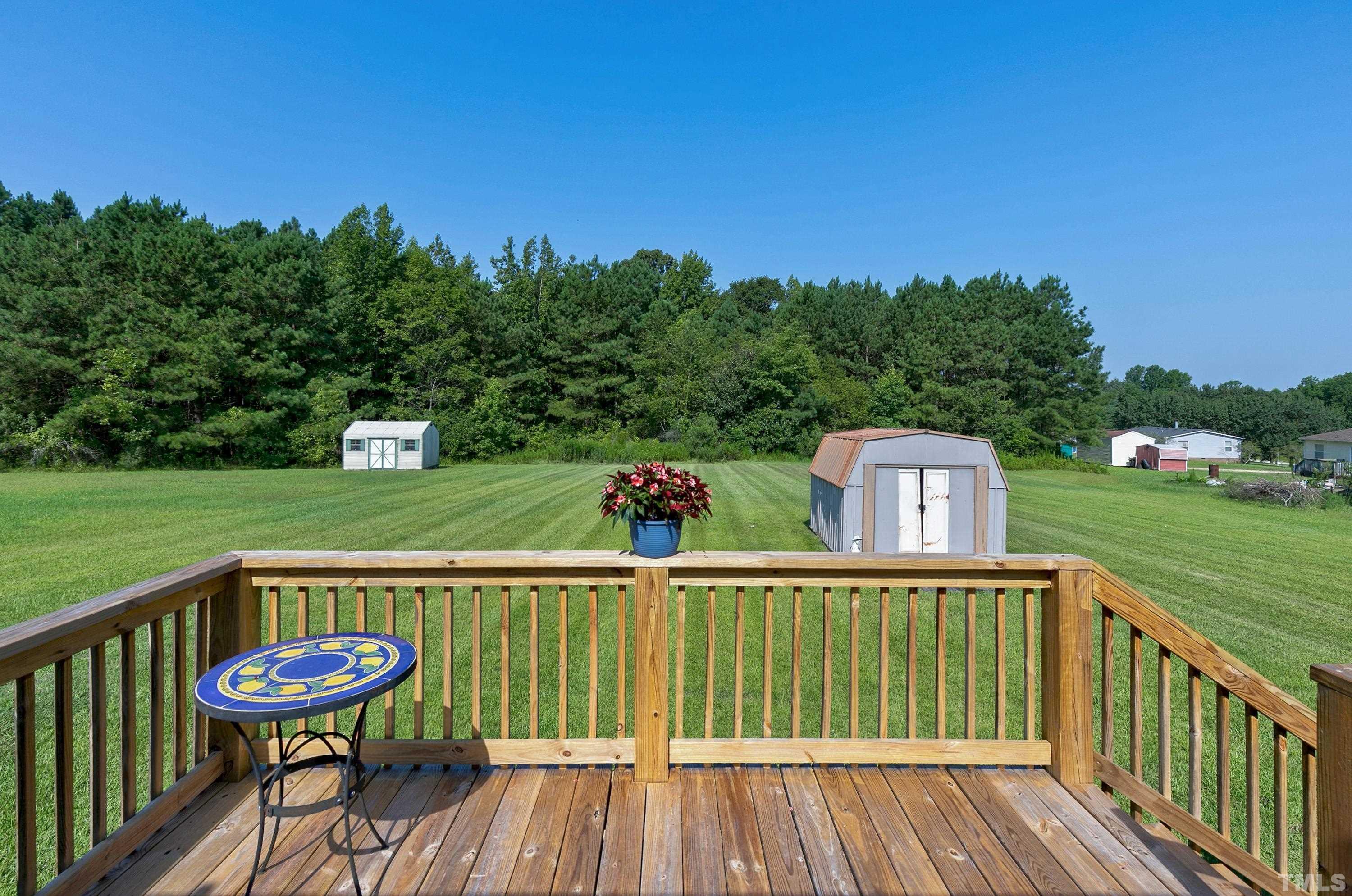 8308 South Creek Road Willow Spring, NC 27592 - Photo 3 of 42 a view of a wooden deck with a garden