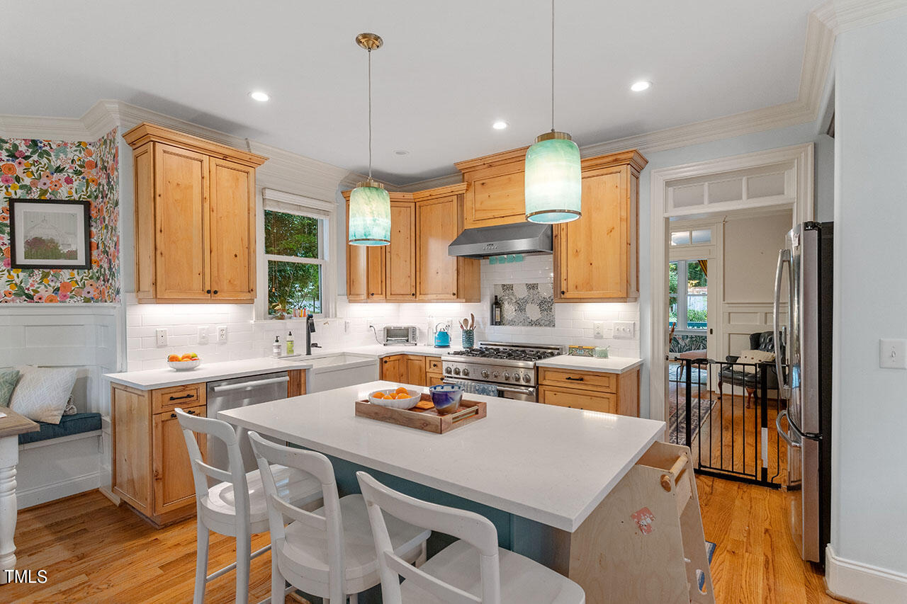 808 Elm Street Raleigh, NC 27604 - Photo 16 of 44 a kitchen with a stove a refrigerator a sink dishwasher a dining table and chairs with wooden floor