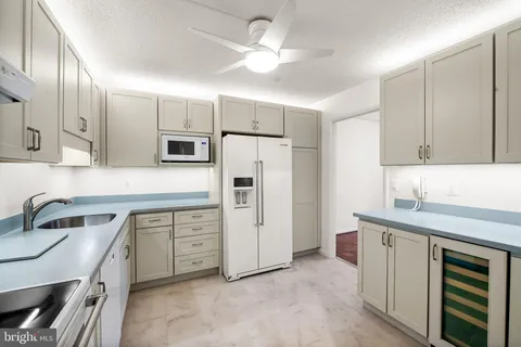 a kitchen with white cabinets and refrigerator