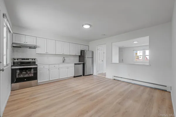 a kitchen with stainless steel appliances white cabinets and wooden floor