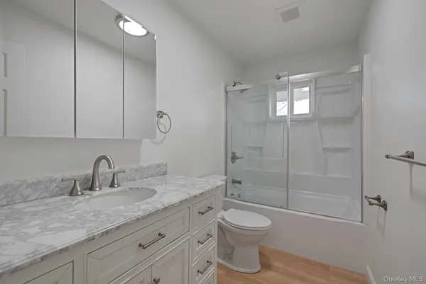 a bathroom with a granite countertop sink a toilet and shower