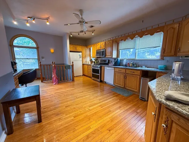 a large kitchen with stainless steel appliances granite countertop a stove and wooden floor