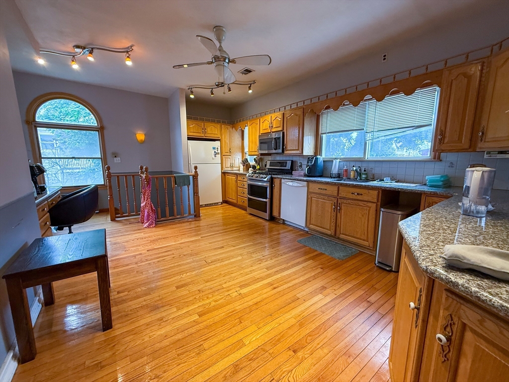 a large kitchen with stainless steel appliances granite countertop a stove and wooden floor