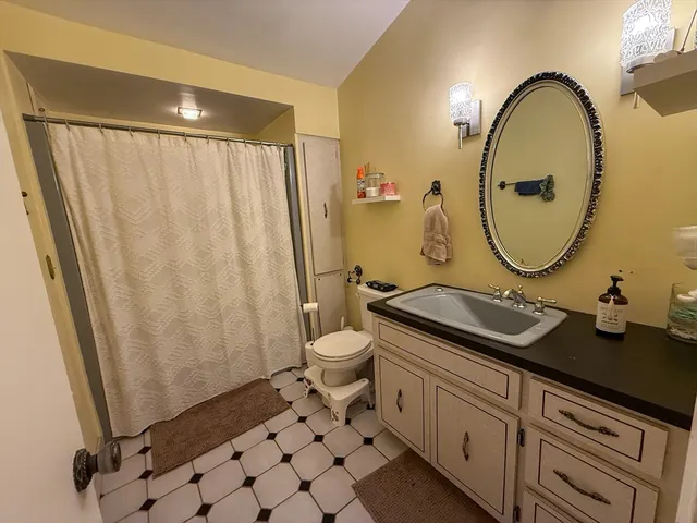 a bathroom with a granite countertop sink mirror and a toilet