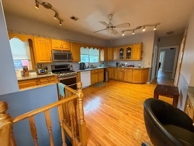 a kitchen with stainless steel appliances wooden floor dining table and chairs