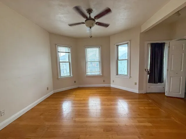 a view of empty room with wooden floor and fan
