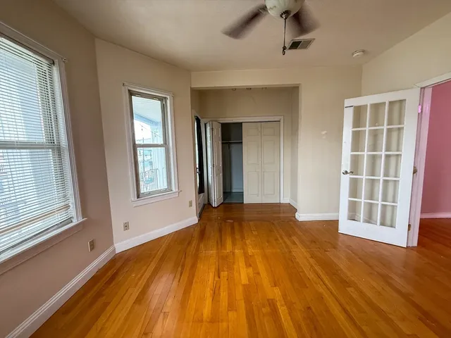 a view of empty room with wooden floor and fan