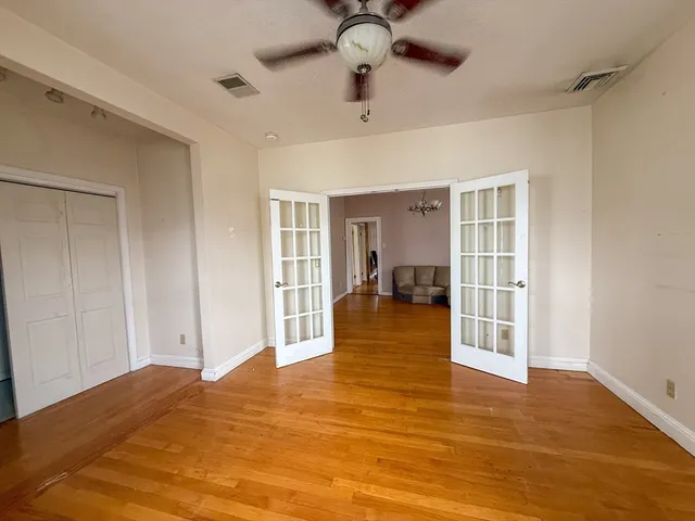 a view of a bedroom with wooden floor and a ceiling fan