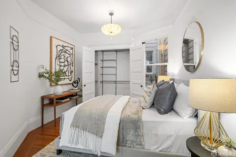 a bedroom with bed a mirror and a potted plant