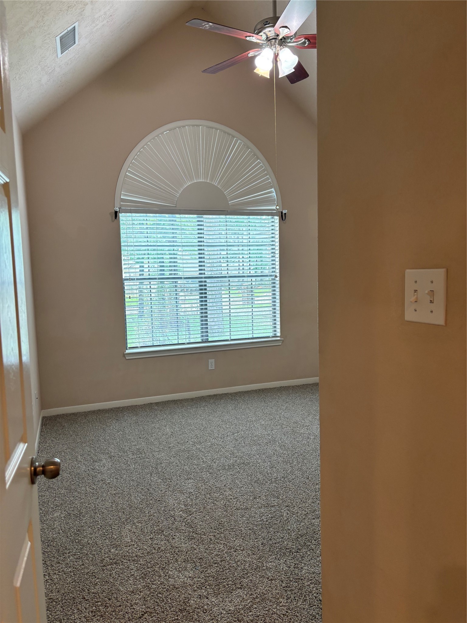 3238 Glenforest Road Montgomery, TX 77356 - Photo 27 of 41 This room features a vaulted ceiling with a ceiling fan, a large arched window with blinds, neutral wall colors, and carpeted flooring, offering a cozy and inviting space.