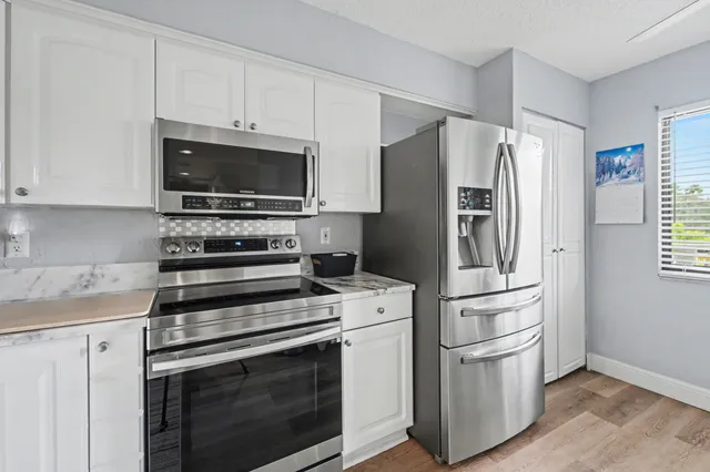 a kitchen with white cabinets and stainless steel appliances