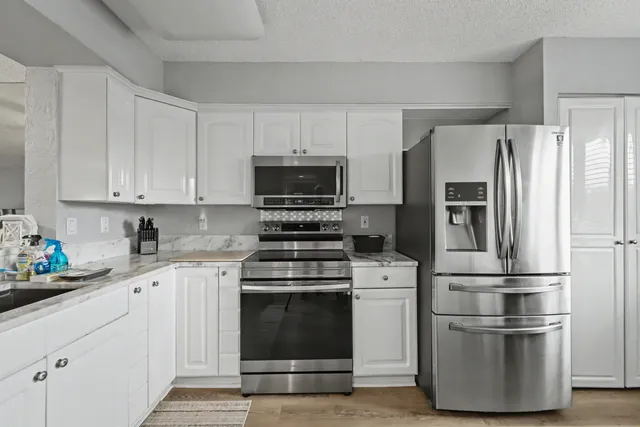 a kitchen with cabinets stainless steel appliances and wooden floor